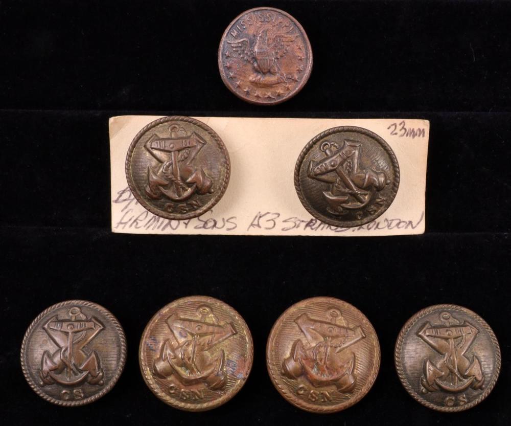 Lot of seven bronze-colored metal buttons with an anchor motif, shown on a dark background and on a small paper card.