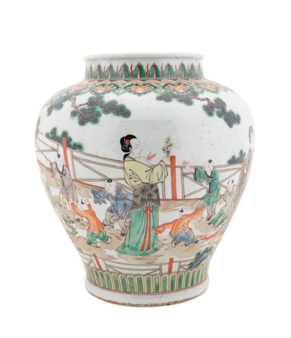 Chinese porcelain jar with green and multicolor painted scenes of people in a courtyard, shown from the front.