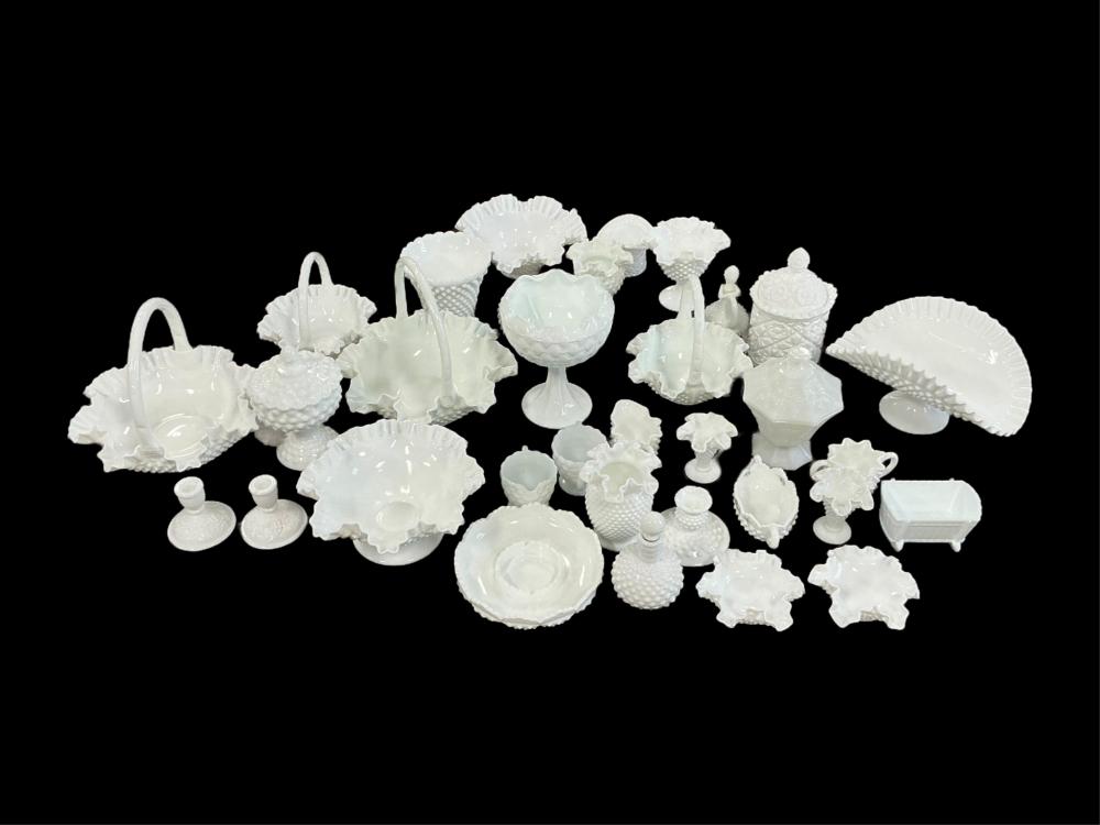 Group of white milk glass decorative pieces on a black background, including dishes, cups, a lidded jar, and small containers.