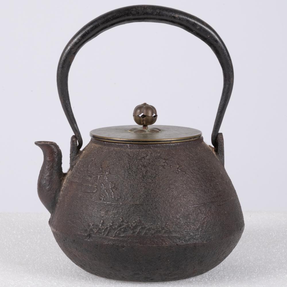 Dark cast-iron teapot with curved handle and rounded body, featuring a lid and knob finial.