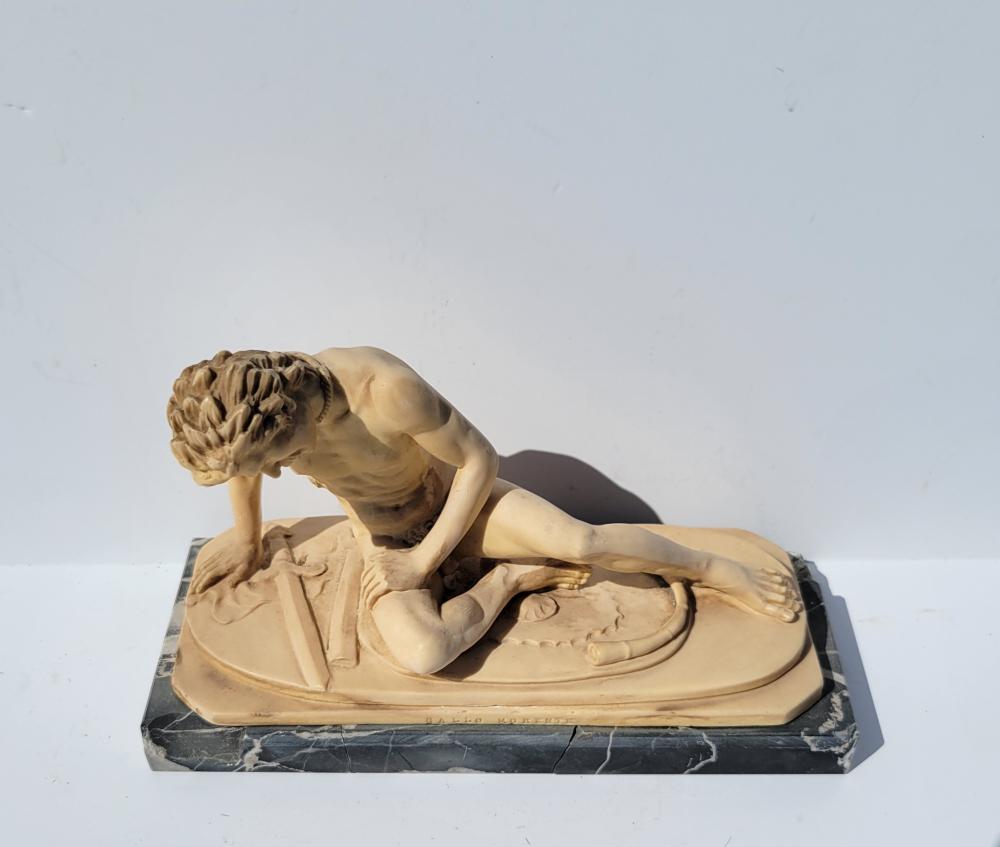 Photograph of a classical-style cast figure statue of a muscular man leaning forward, holding his head, posed on a black marble-style base.