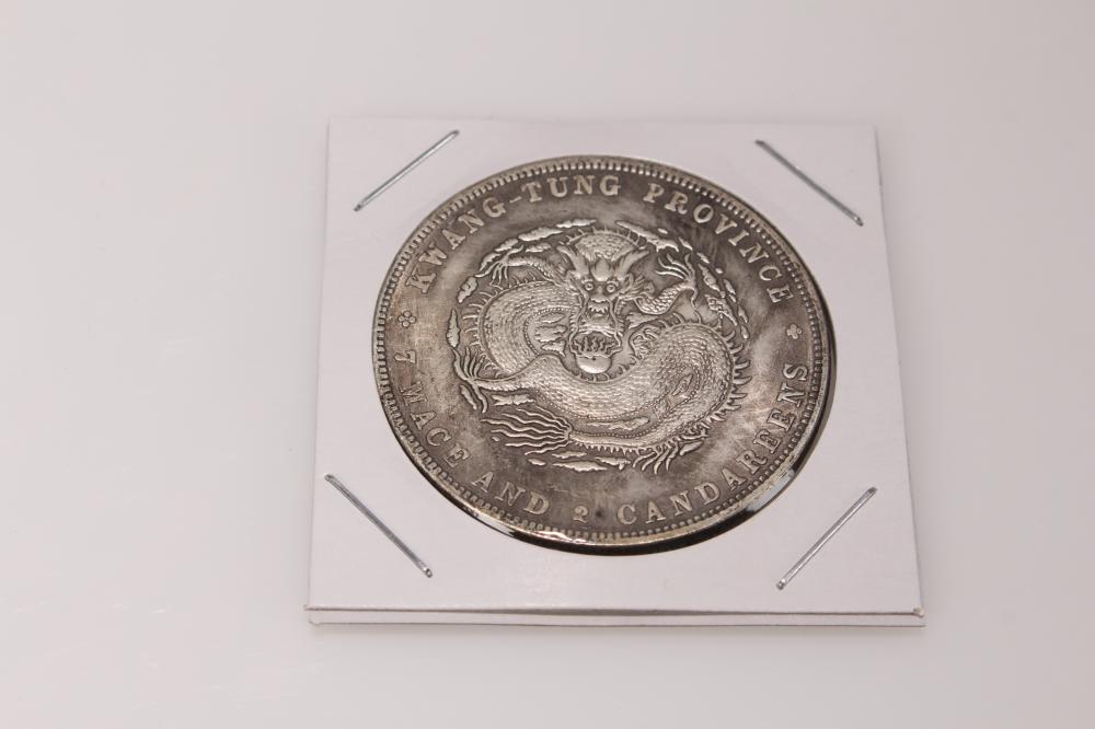 Silver-colored coin with a dragon design at the center, shown inside a white display holder with four metal prongs.