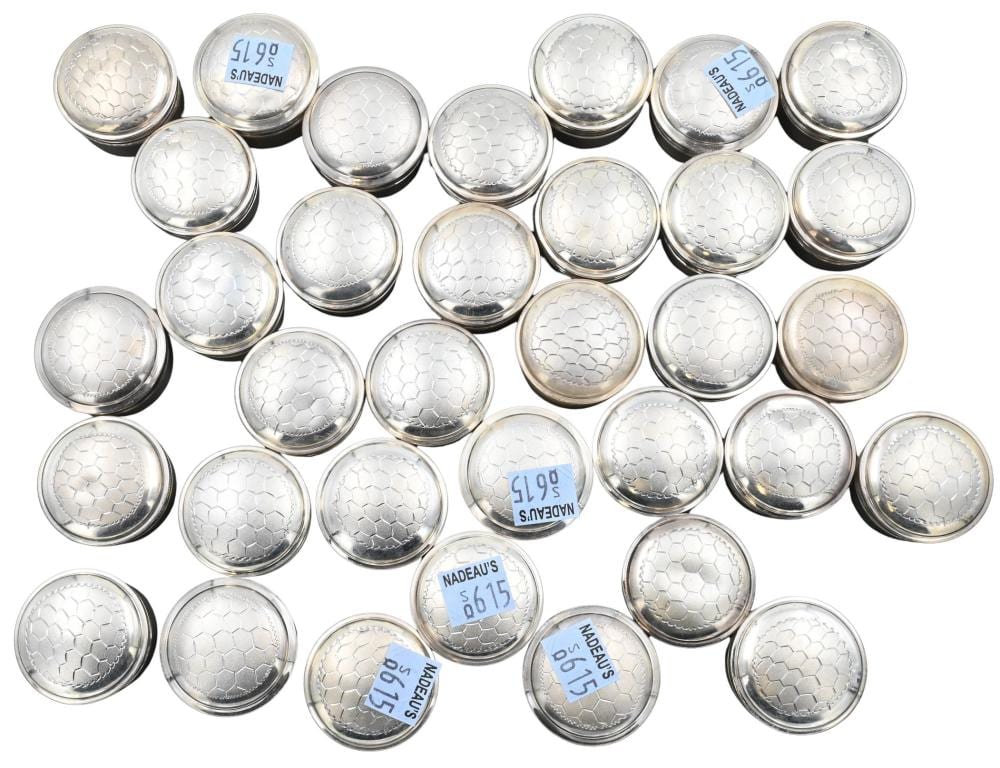 Round silver pill boxes with textured honeycomb-pattern lids, arranged in a grid and shown from above