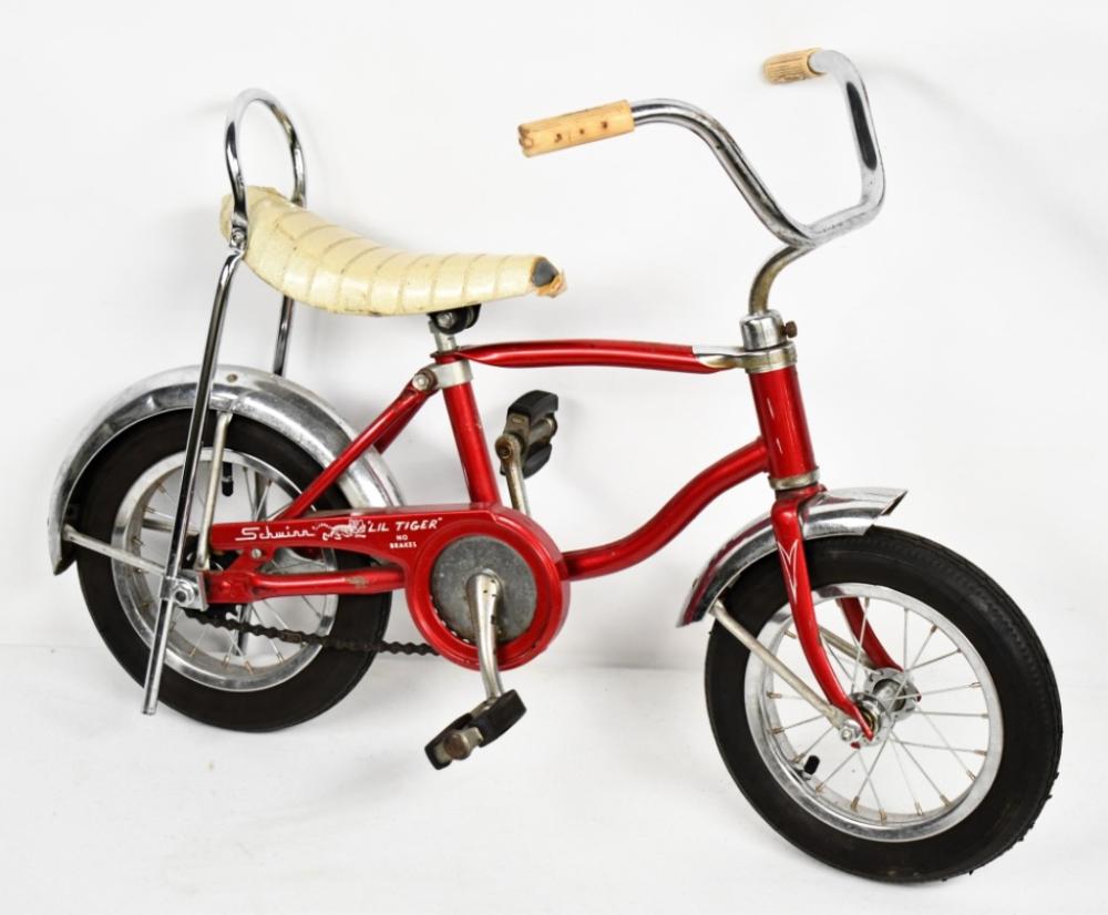 Small red child’s bicycle with black tires, chrome handlebars, and a front fender, shown against a white background.