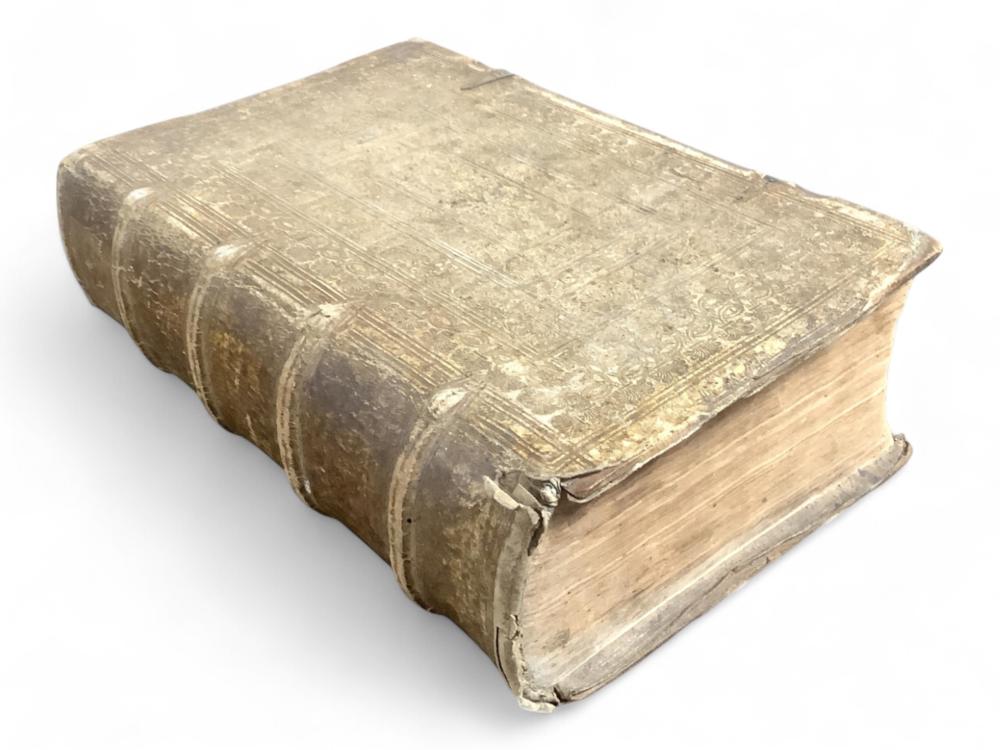 Antique bound book with worn leather cover and decorative blind-stamped pattern, shown closed at an angle with edges visible.