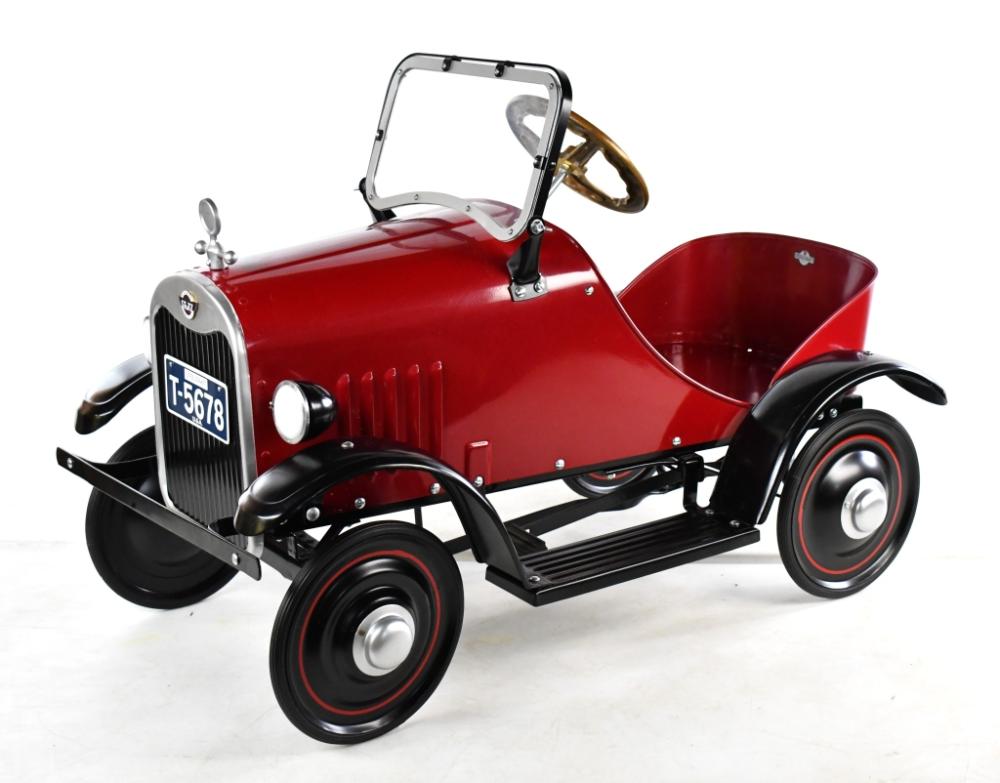 Red pedal car with black fenders, chrome grille, and steerable front wheels on a white background.