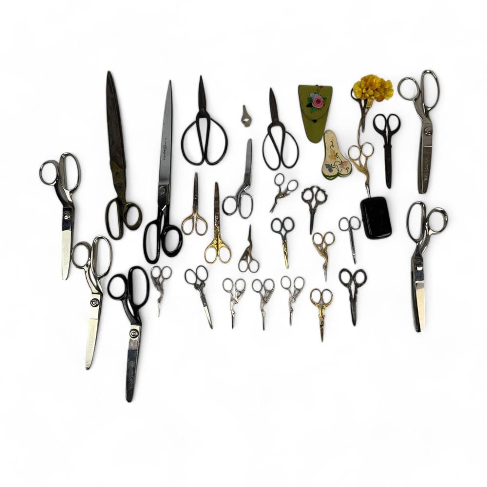 Assorted vintage scissors and shears of different sizes arranged on a white background.