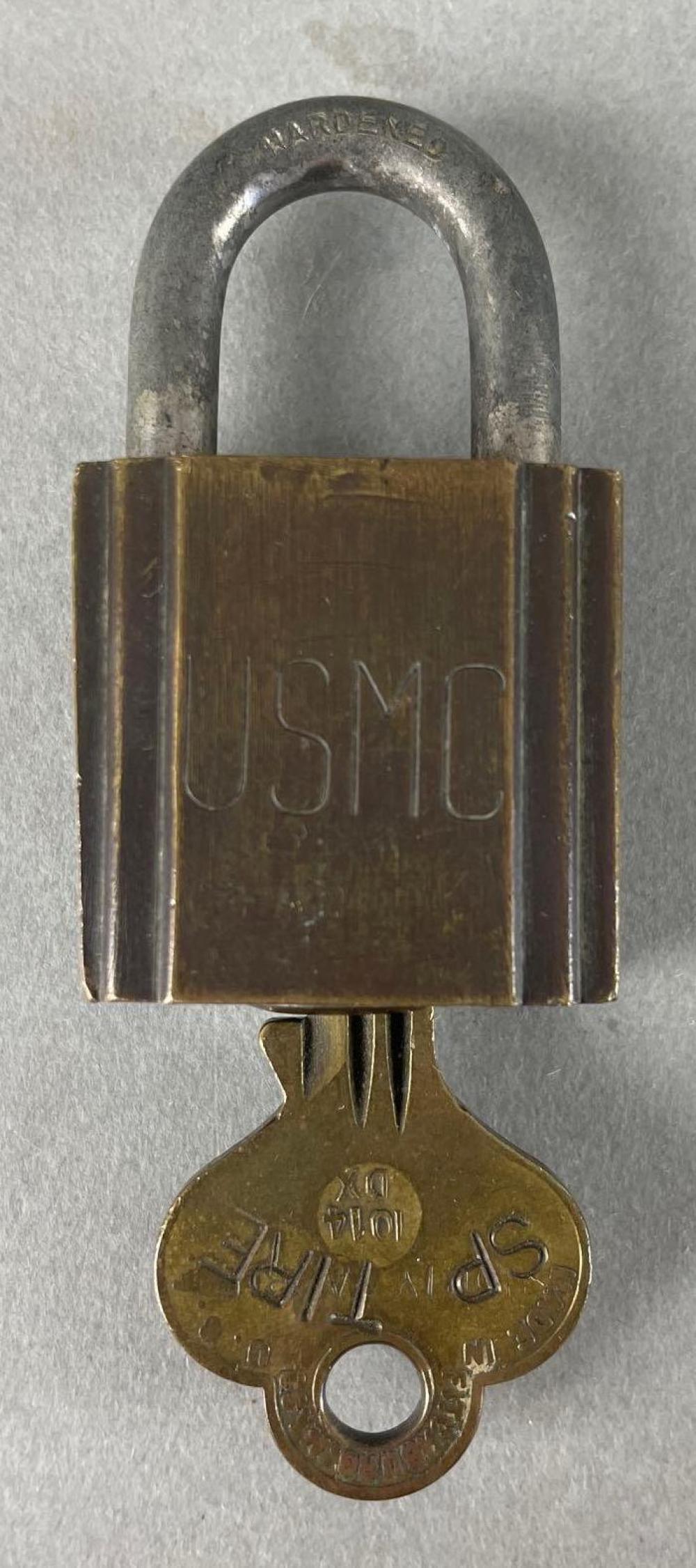 Vintage padlock and key on a gray background, shown close-up with the lock shackle arched over the rectangular body.