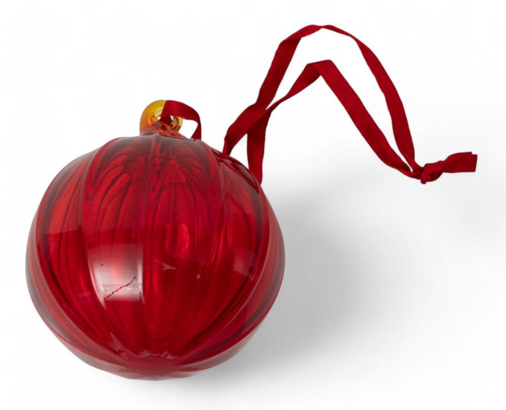 Red faceted blown glass Christmas ornament with a looped red ribbon hanger on a white background.