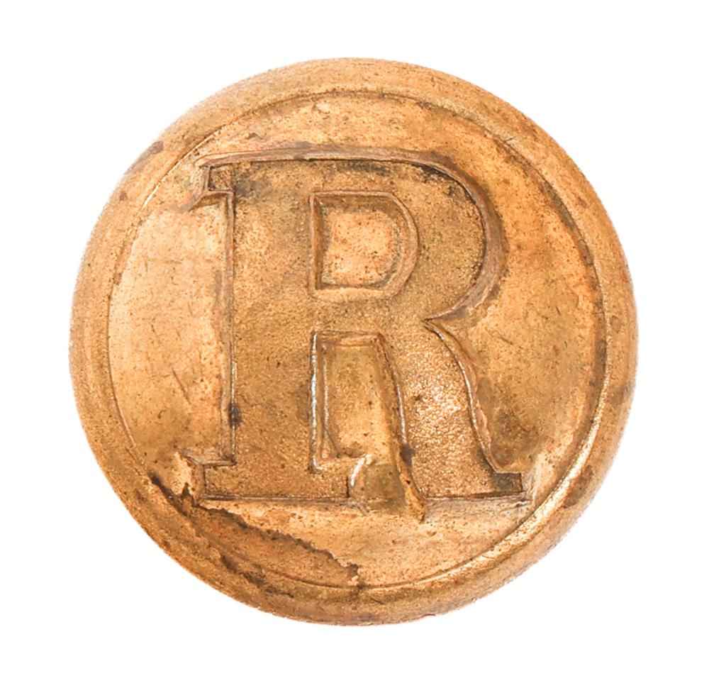 Close-up of a round metal button with raised letters "R" and "F" in a decorative border.
