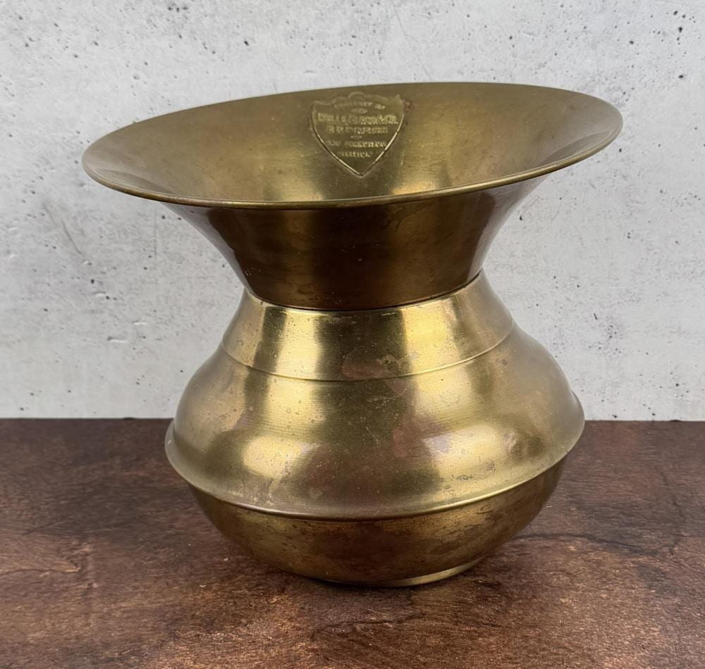 Brass spittoon with a flared top and rounded base, featuring an engraved crest on the interior