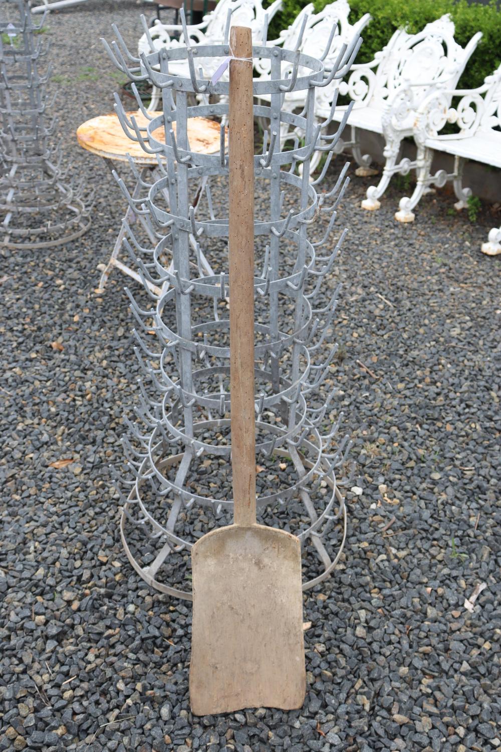 Antique style wooden grain shovel with a long handle and metal rakes arranged in a circular cage behind it