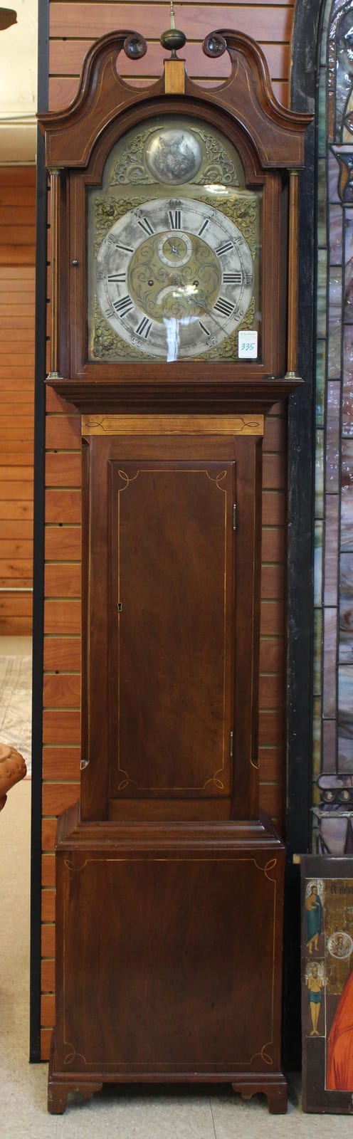 Antique wooden grandfather clock with a glass clock face, Roman numeral dial, and decorative arch top panel.