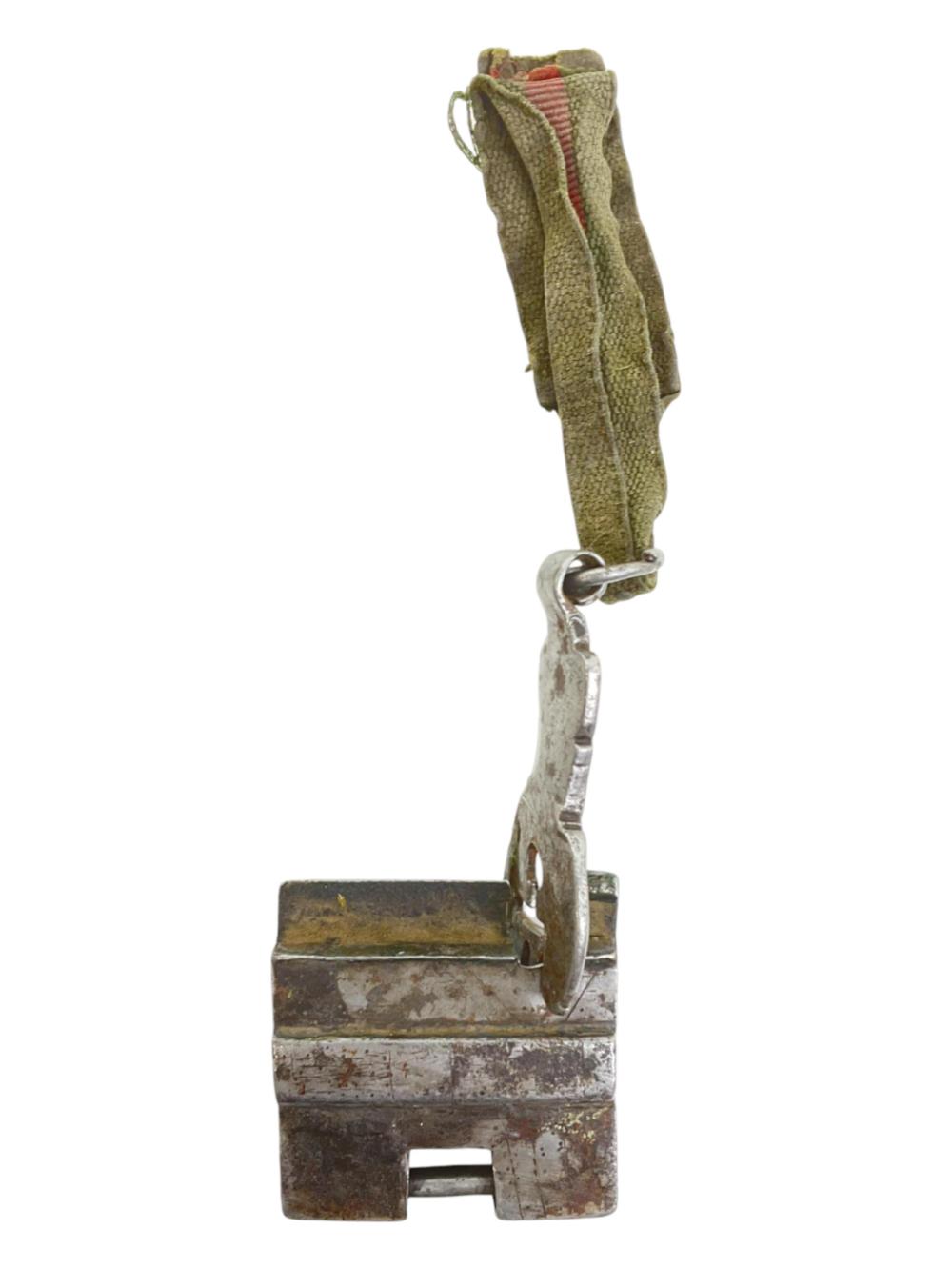 Antique-style metal door lock with attached key, showing a rectangular lock body and a small looped ring holding the key.