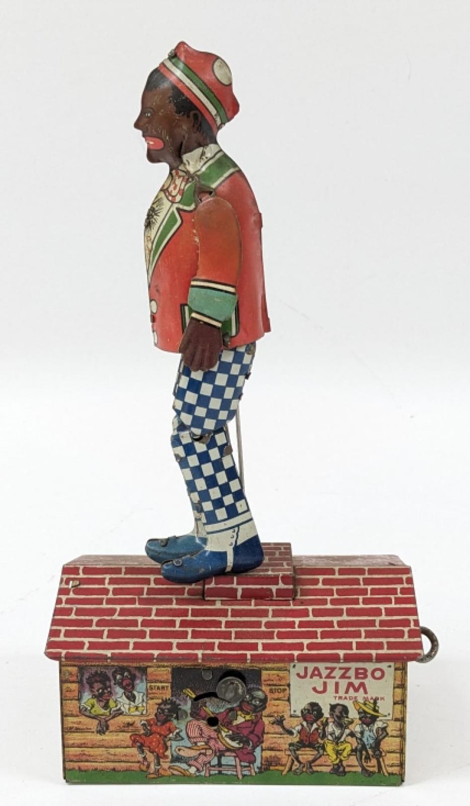 Wind-up tin litho toy figure of a man playing musician costume, standing on a brick-style box with “JAZZBO JIM” label.
