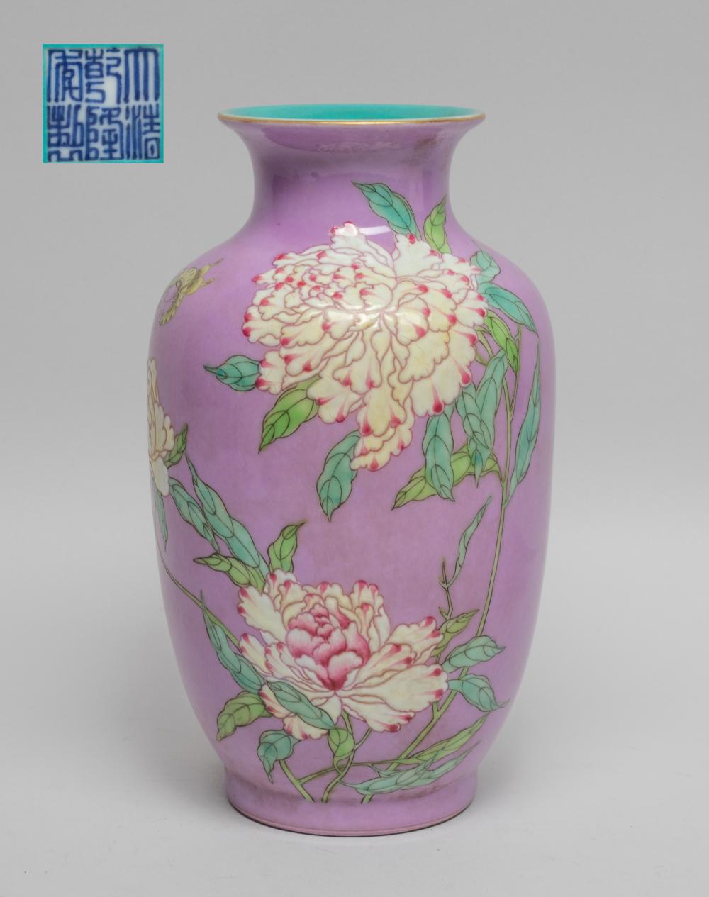 Purple porcelain vase with turquoise rim and multicolored peony blossoms with green leaves in a floral design.