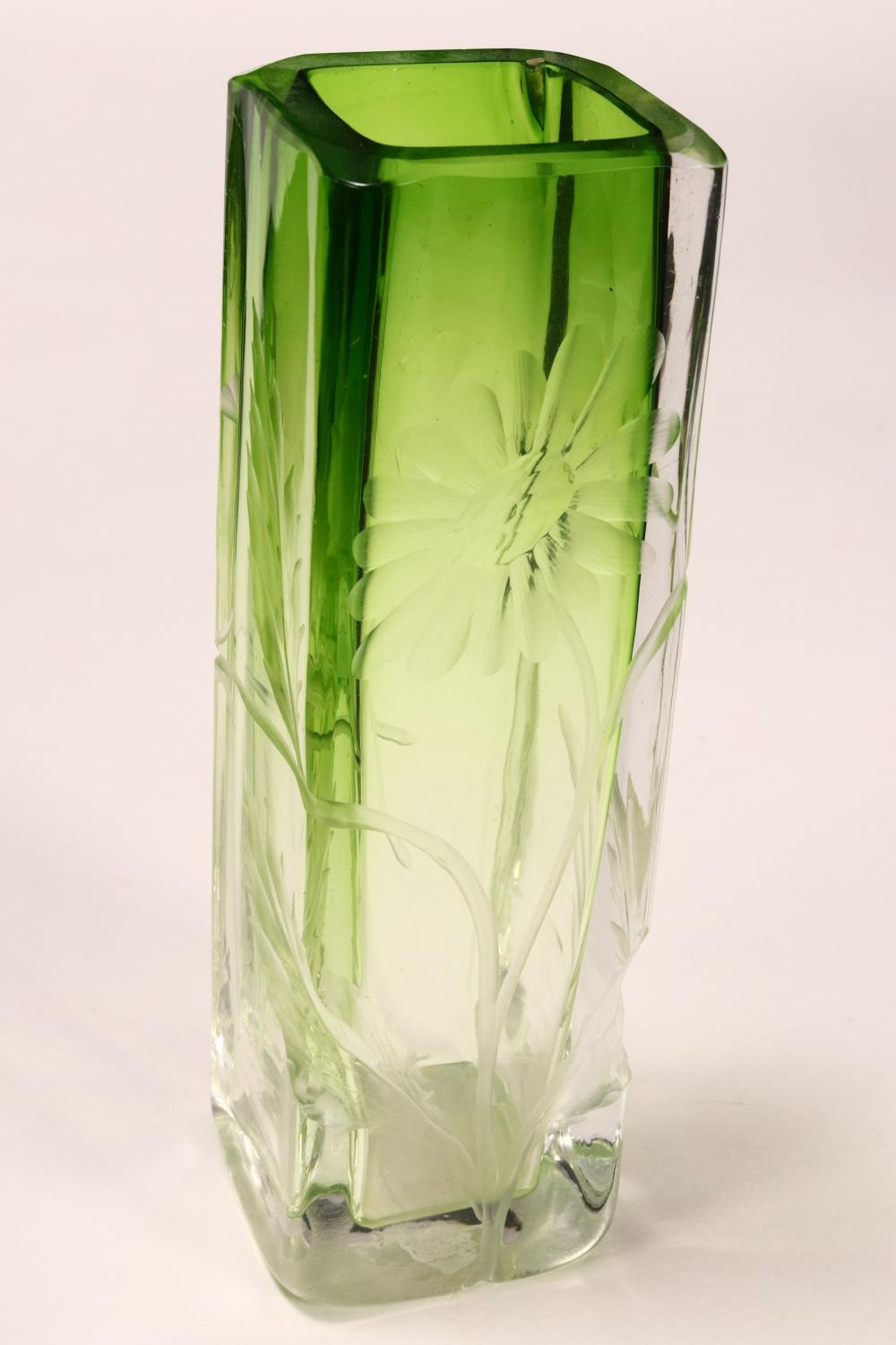 Green glass vase with clear facets and a flower-like cutout design in the lower center, photographed against a light background.