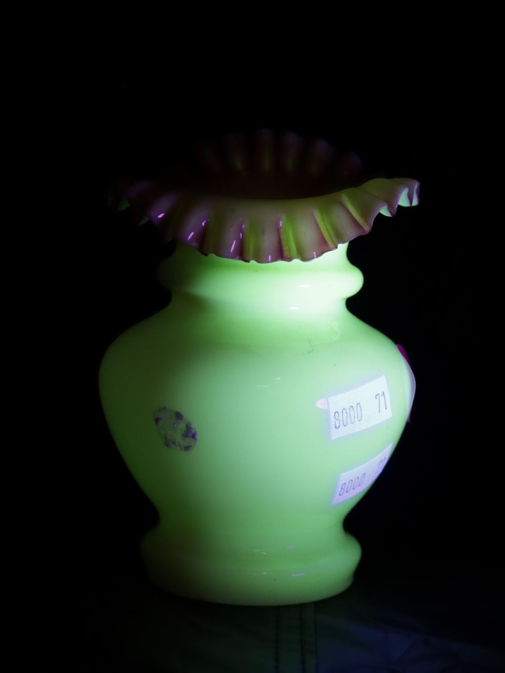 Green and translucent glass vase with a fluted top rim and ruffled, pink edge