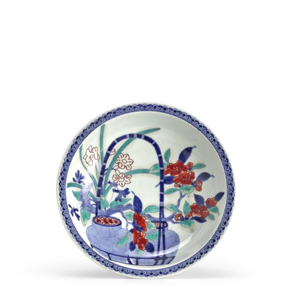 Porcelain round dish with blue border and floral decoration in red, blue, and green over a white background.