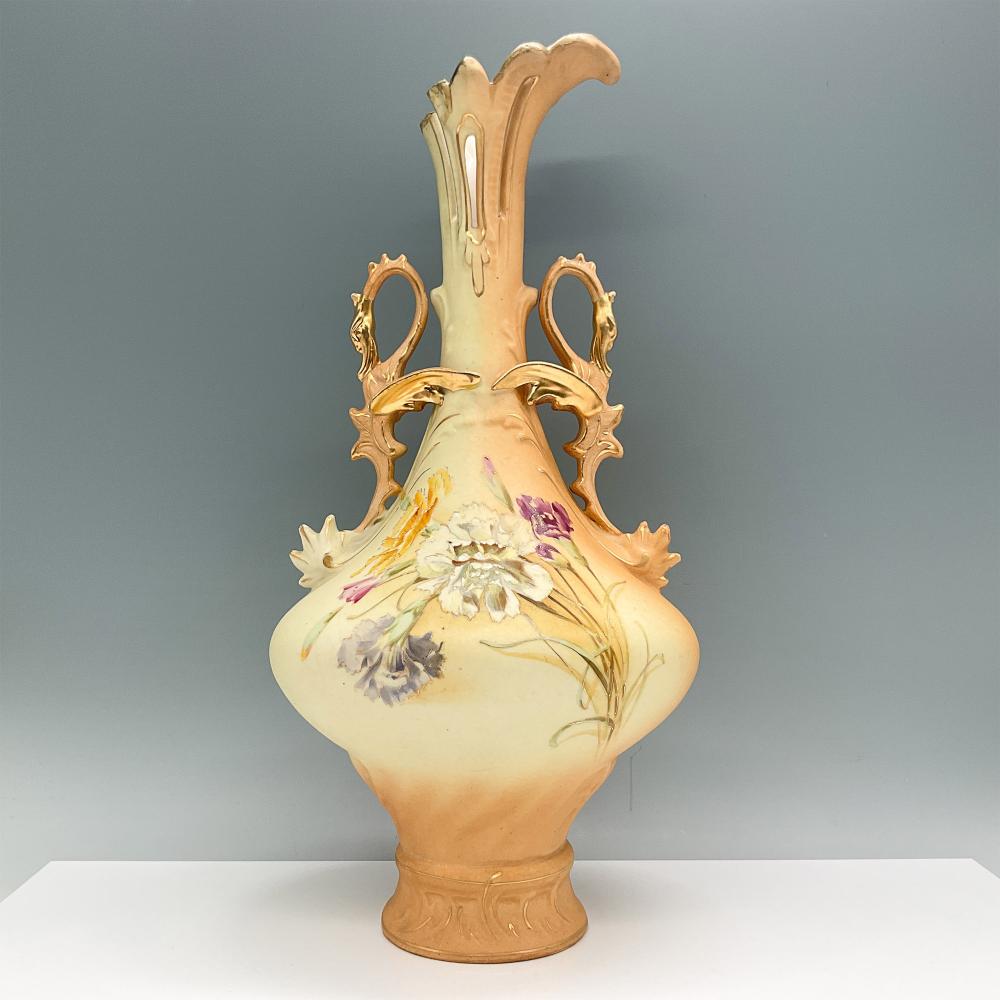 Ornate cream ceramic vase with gold-toned handles shaped like dragons and a floral painted design on the front.