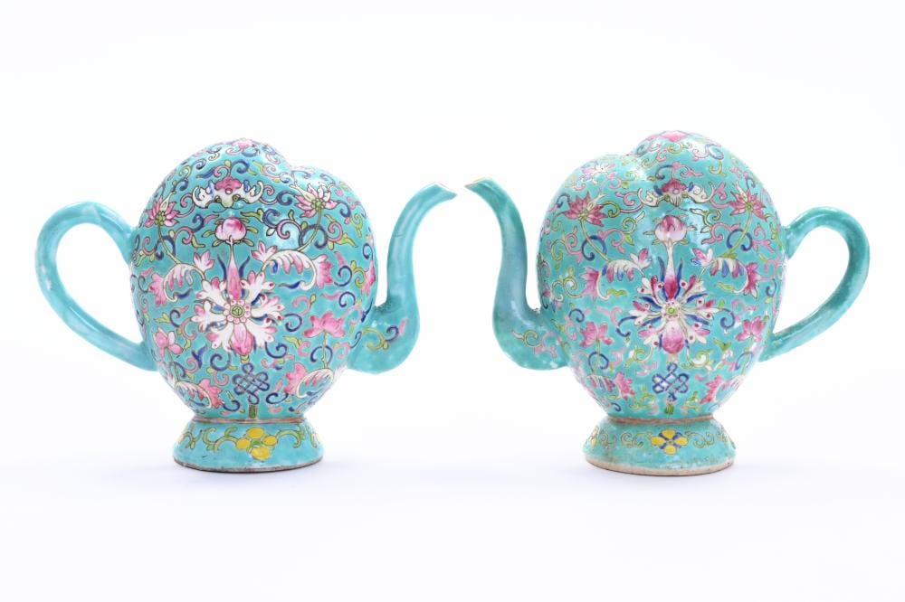 Photo of two matching turquoise enamel-style teapots with peach-shaped bodies, curved spouts, and floral medallion designs in pink and gold.