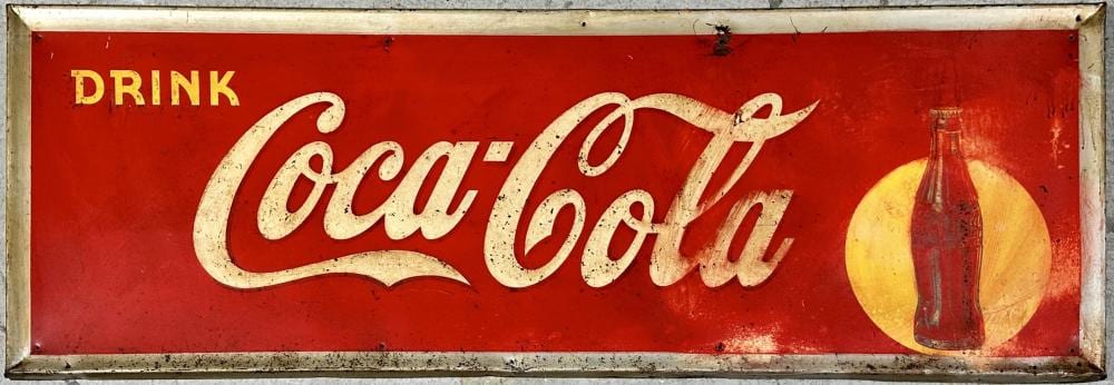 Vintage red metal tin sign reading “DRINK Coca’Cola” with a yellow circle and a bottle graphic on the right.