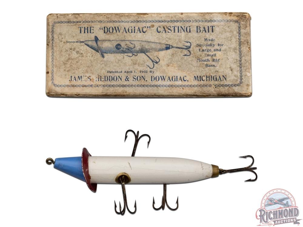 Vintage fishing lure with a blue-and-white body, red front, and three treble hooks shown with its paper storage box above.