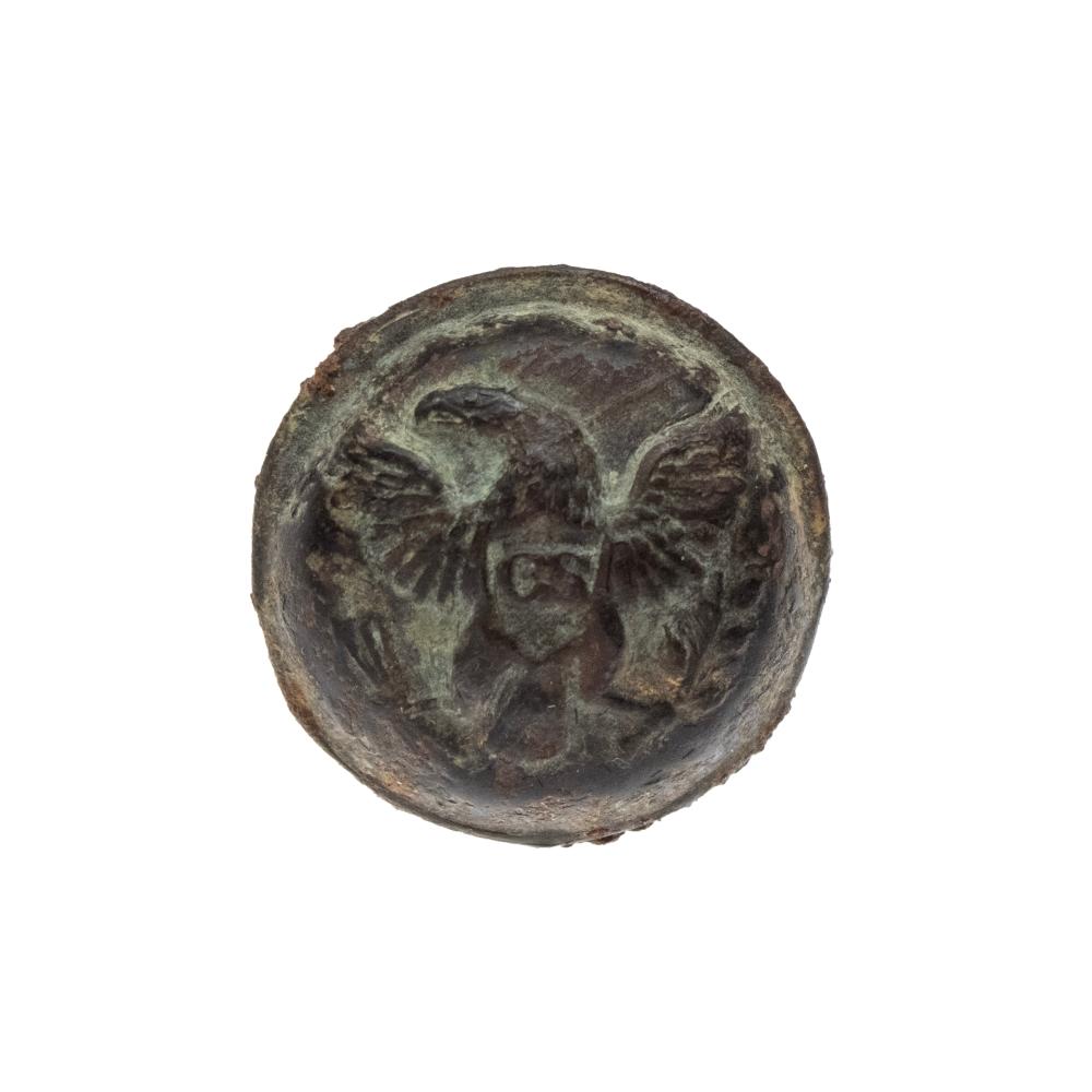 Round metal button featuring an eagle with a shield-like emblem in the center.