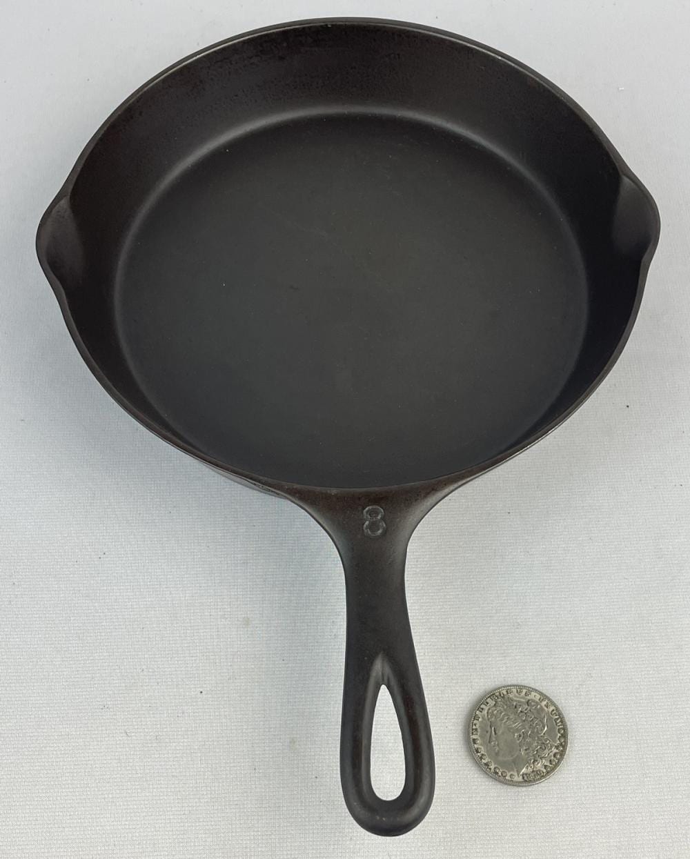 Black cast iron skillet with a single handle, photographed from the top against a light background.