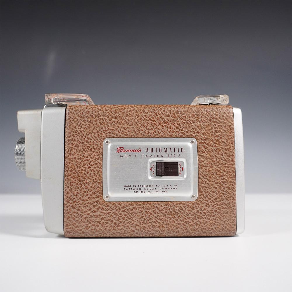 Front view of a Kodak Brownie Automatic movie camera with a brown textured leatherette body and a silver nameplate.