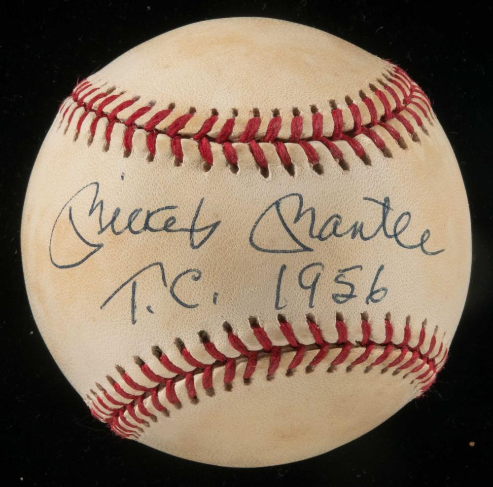 Close-up of a signed baseball with blue ink signatures across the center and red stitching visible around the surface.