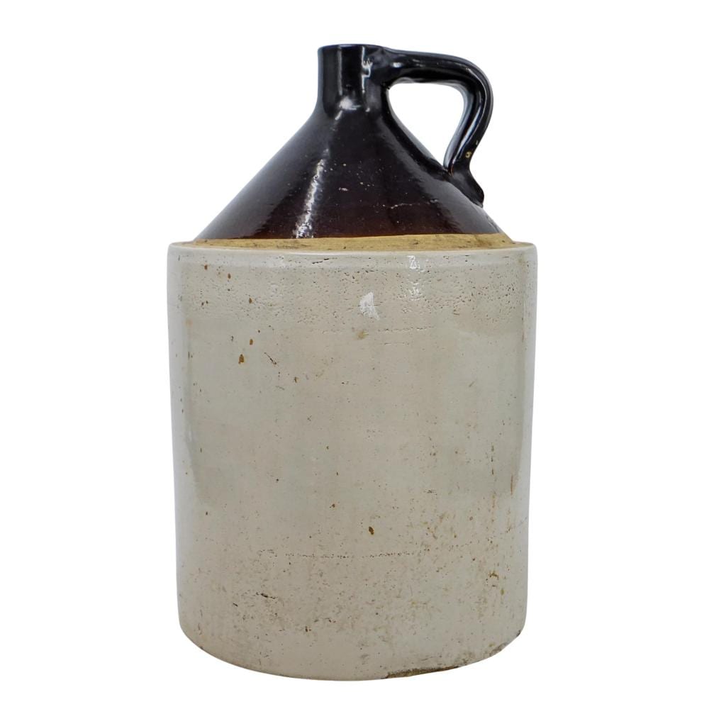 Vintage stoneware whisky jug with a dark brown glaze top and a white speckled body, shown with a curved handle and spout.