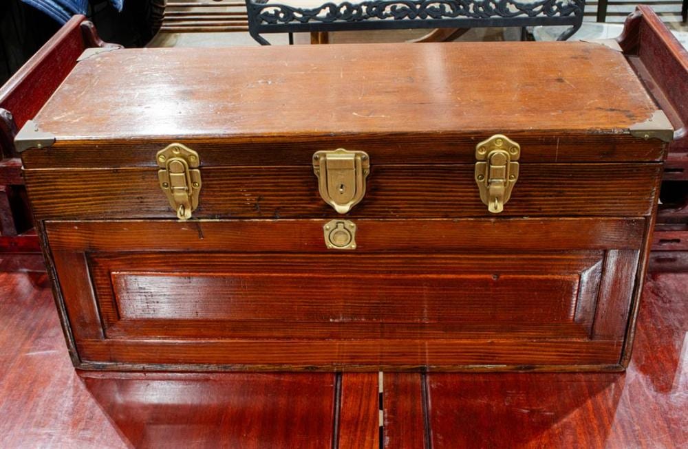 Antique wooden sewing box with brass latches and a hinged front panel, shown open on a table.
