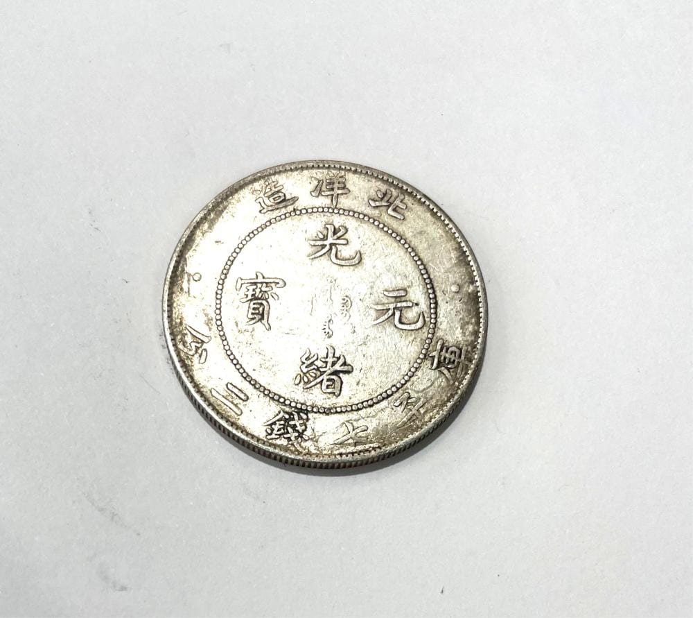 Close-up of a round Chinese coin with four characters inside a central square and a beaded border.