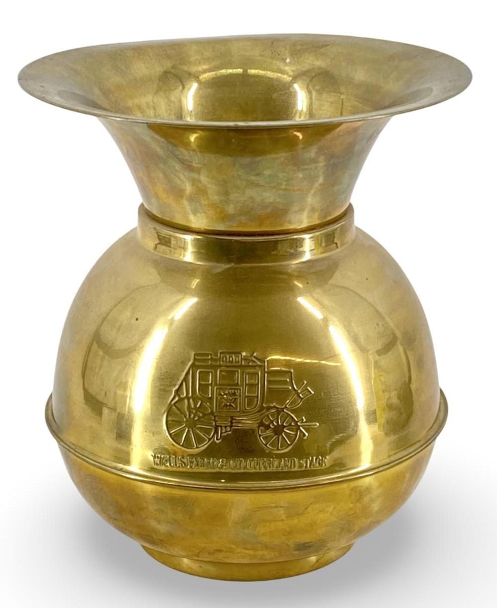 Brass spittoon with a flared rim and wagon-style emblem relief on the front, photographed against a white background.