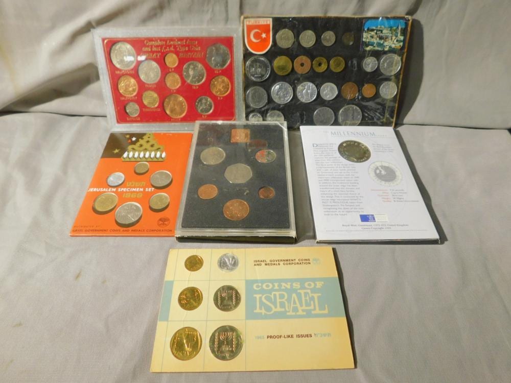 Six coin set packages arranged on a table, showing multiple small coins in display cards and sleeves.