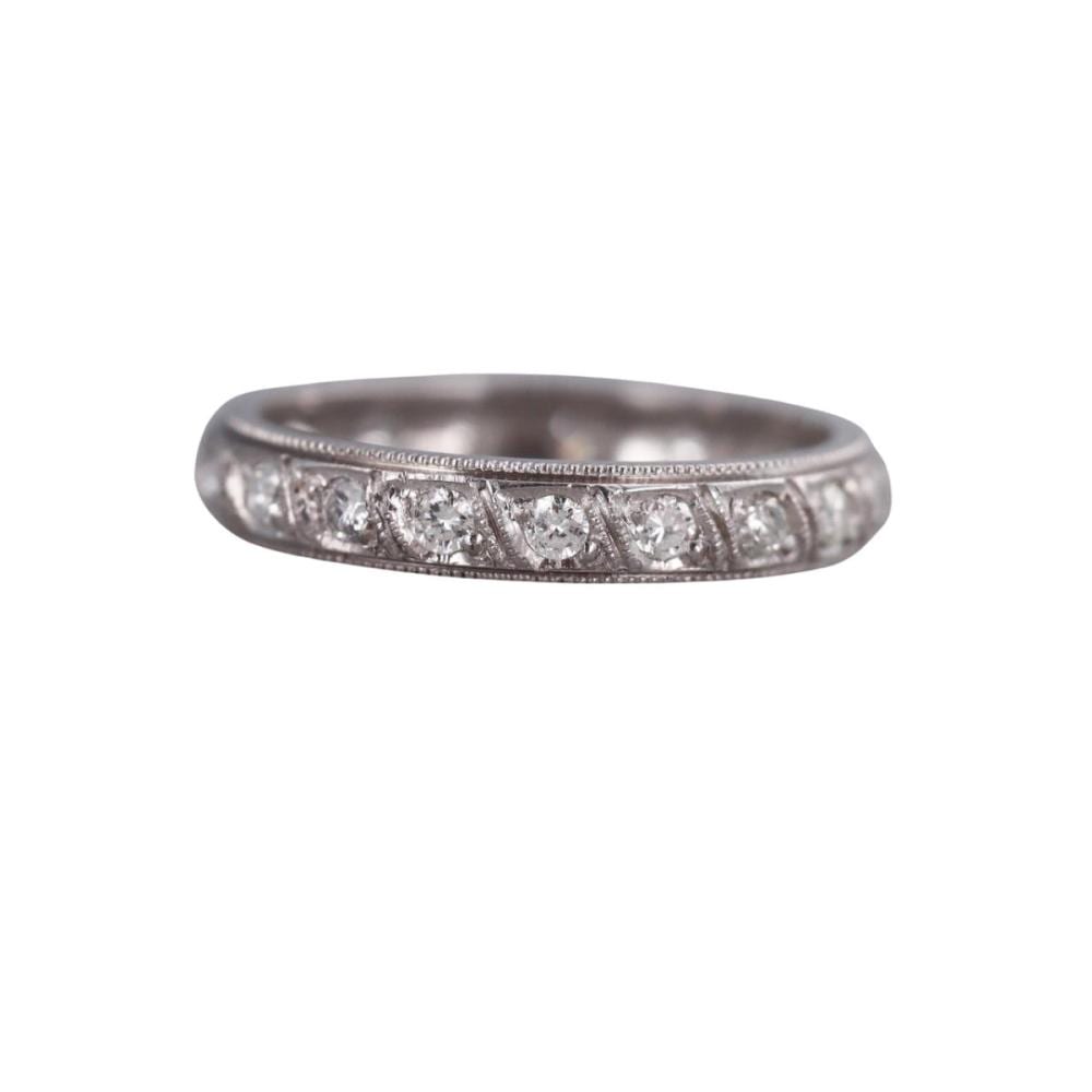 Close-up of a silver-toned diamond eternity wedding band ring with small round stones set in a row across the front.