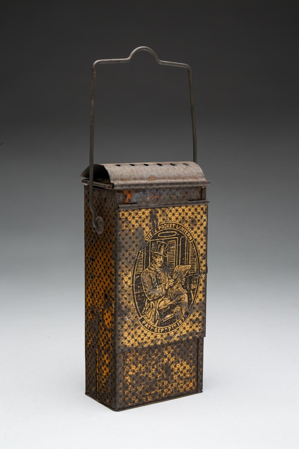 Vintage pocket lantern with arched handle and printed graphic panel, shown on a studio background.