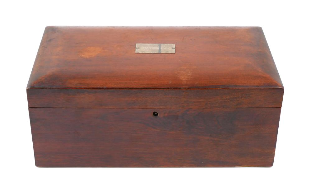 Brown wooden box with a rectangular metal label on top and a small knob on the front panel.