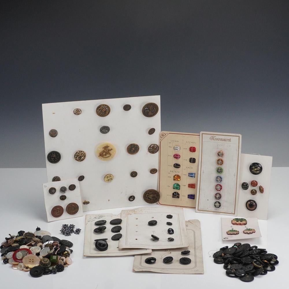 Group of assorted antique-style buttons and small jewelry pieces laid out on display cards on a white surface.