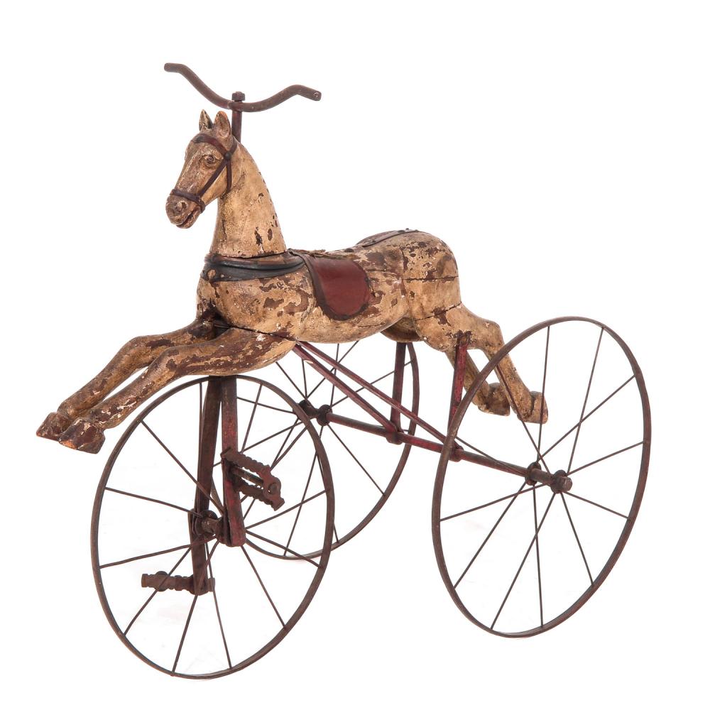 Antique wooden toy tricycle with a horse-shaped head and two large spoked wheels, photographed against a white background.