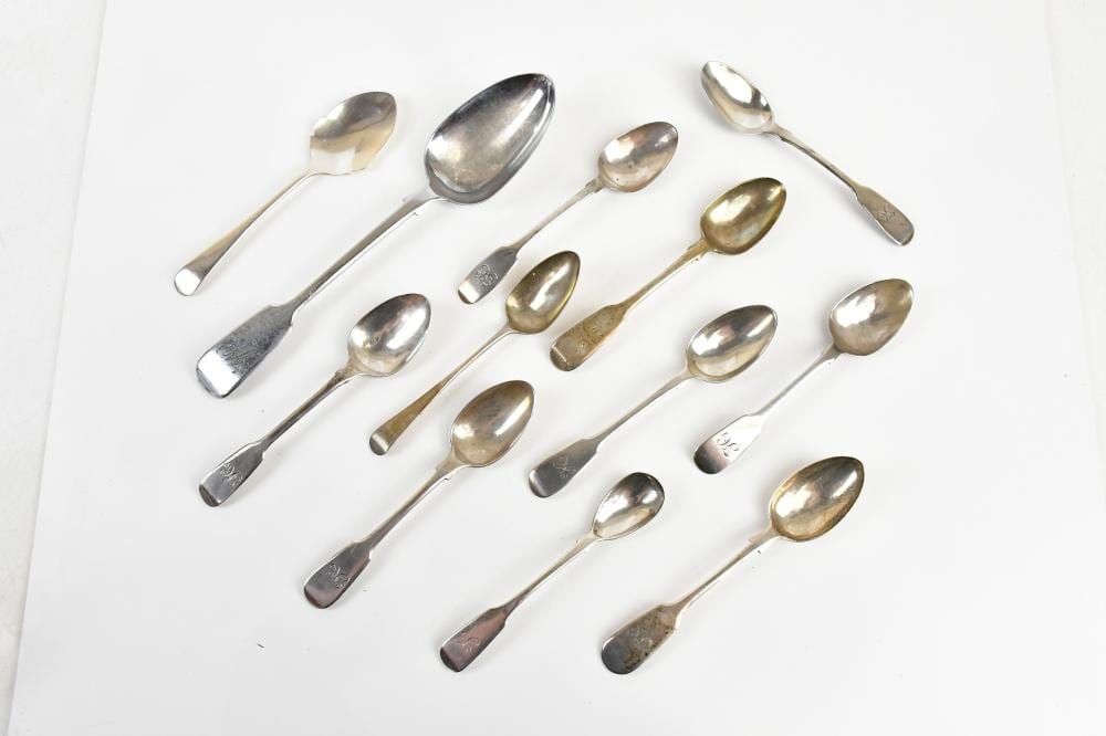 Group of hallmarked silver teaspoons and a silver tablespoon with polished bowls, arranged on a white background.