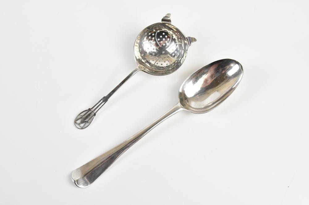 Two small silver-colored metal spoons on a white background, including a round straining spoon and a long-handled tablespoon-style spoon.
