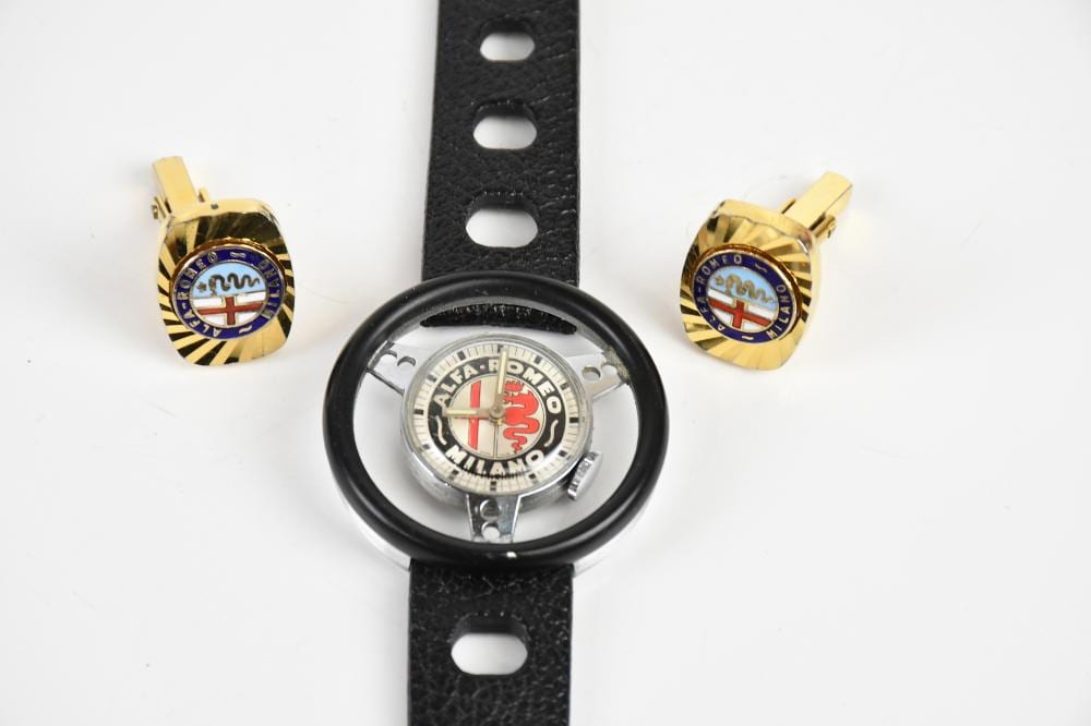 ALFA ROMEO; a novelty stainless steel wristwatch, the face decorated with the Alfa Romeo emblem, the glass signed 'Old England', and a pair of Alfa Romeo cufflinks. sold by Adam Partridge Auctioneers, lot 1684 — auction record photograph