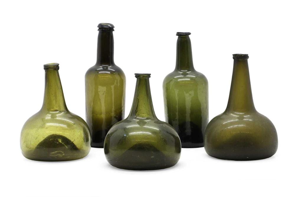 Five green glass bottles with dark caps arranged on a white background.