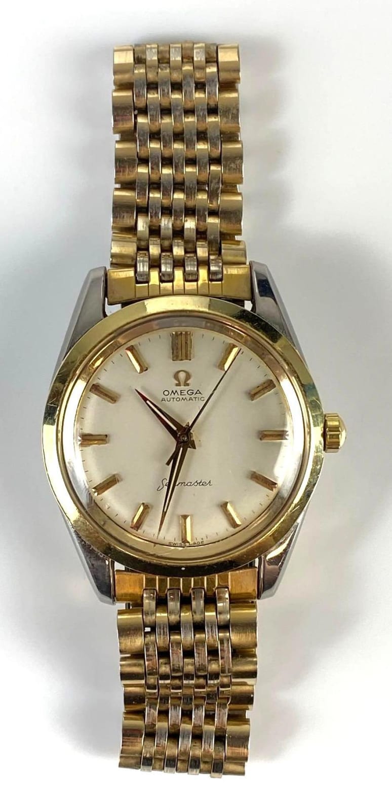 Gold-tone metal wristwatch with a round champagne dial, baton hour markers, and a bracelet strap, shown front view.