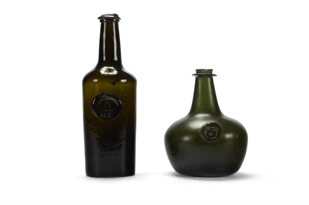 Two dark glass bottles with rounded onion-shaped bodies, each with a small crest-like medallion on the front.