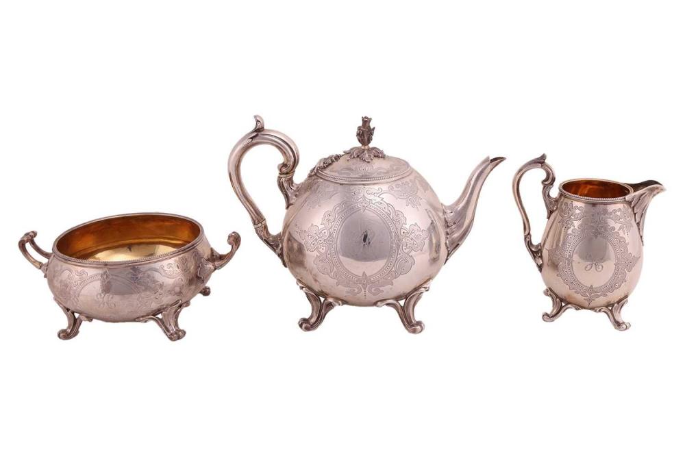 A Victorian three-piece tea set; circular with beaded border, leaf-capped scroll handles, paw feet. The teapot with cast bud final and ivory insulators to the handle, the sugar basin and milk jug with gilt interiors, scroll engraved decoration to... sold by Dawsons Auctioneers, lot 358 — auction record photograph