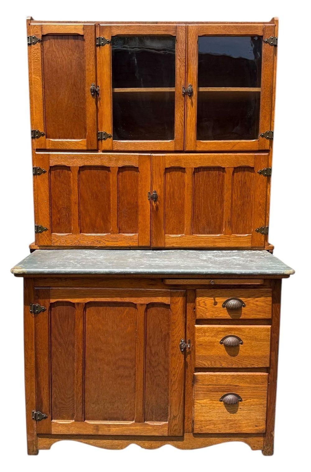 Antique-style oak Hoosier kitchen cabinet with glass doors above and a countertop below, shown front view.