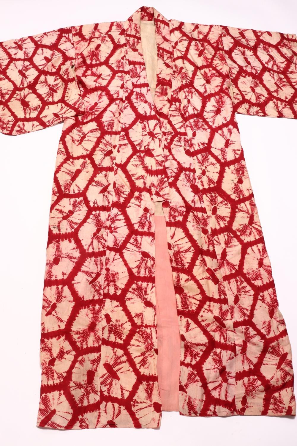 Red and white Japanese kimono with long sleeves and an open collar, patterned with repeating floral and geometric motifs.